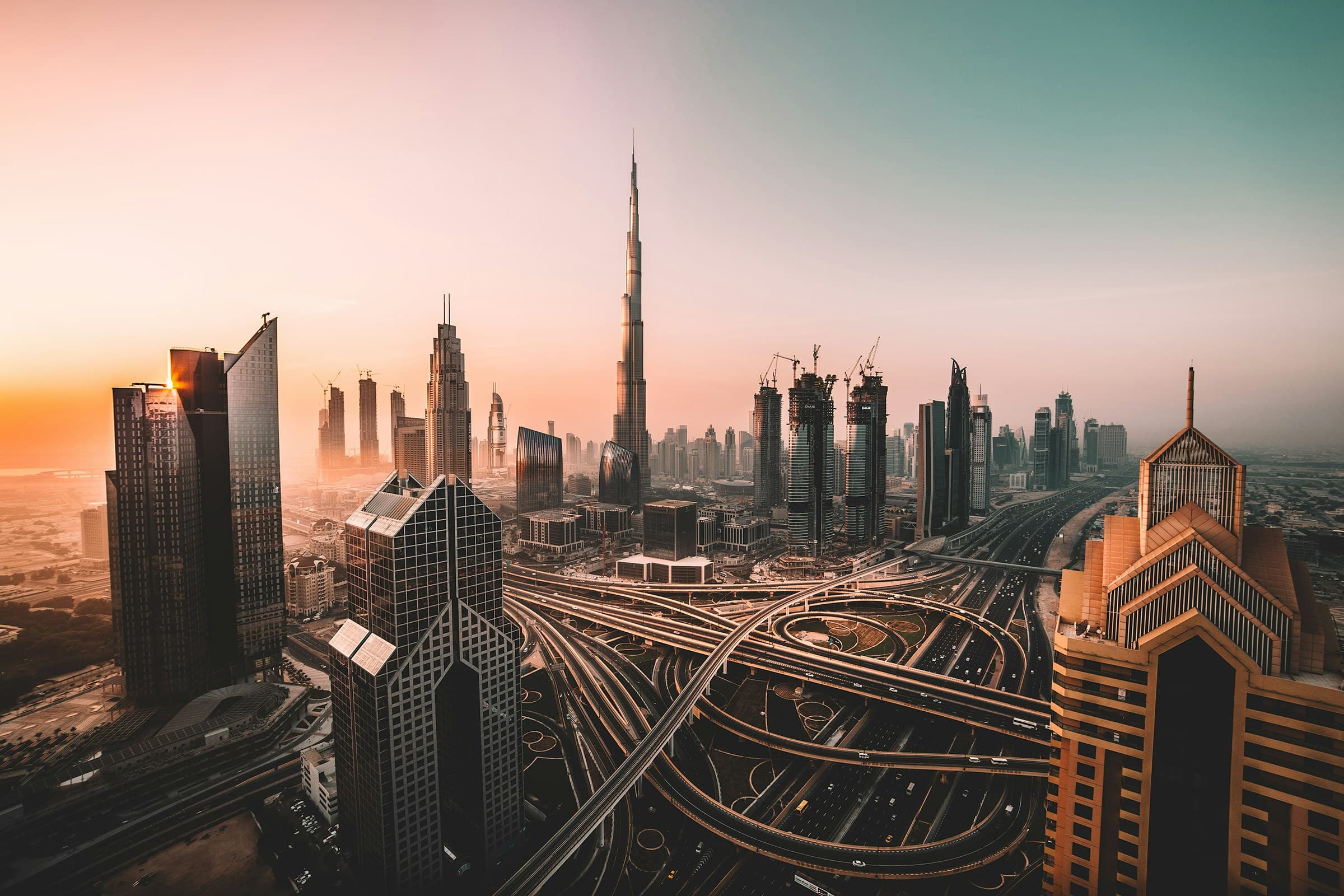 The Burj Khalifa and the Downtown Dubai skyline above a multi-level highway interchange.