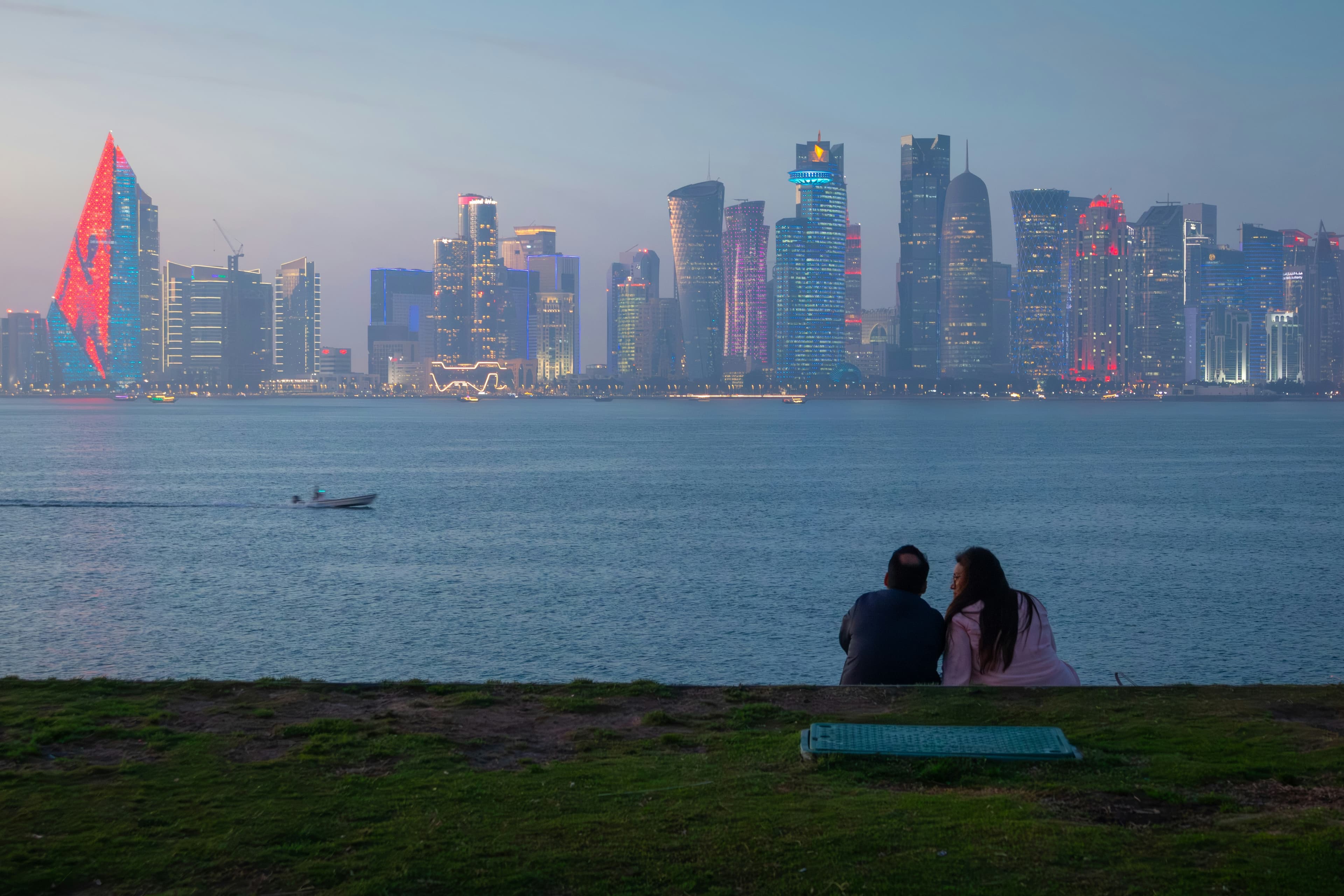 The illuminated Doha skyline seen across the waterfront at night.